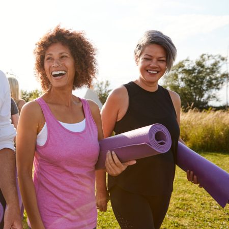 Group Of Mature Men And Women With Exercise Mats At End Of Outdoor Yoga Class