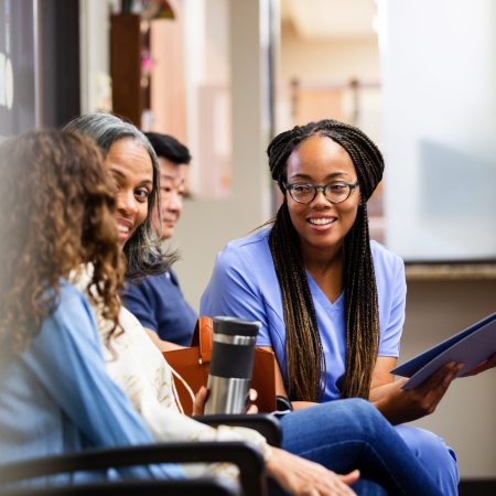 A mid adult nurse and a mature adult grandmother talk with an unrecognizable young teen girl.