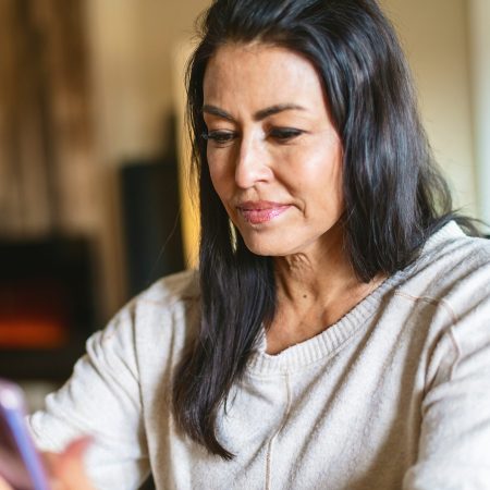 In Western Colorado Mature Adult Female of Hispanic Ethnicity Using Smart Phone In the Home Photo Series Matching 4K Video Available (Shot with Canon 5DS 50.6mp photos professionally retouched - Lightroom / Photoshop - original size 5792 x 8688 downsampled as needed for clarity and select focus used for dramatic effect)