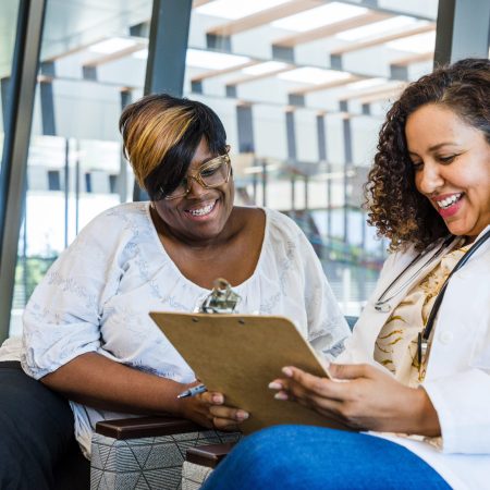 The mid adult female gynecologist smiles as she shares good test results with her mature adult female patient.