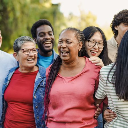 Happy multi generational people having fun together at city park while hugging each other - Multiracial friends concept